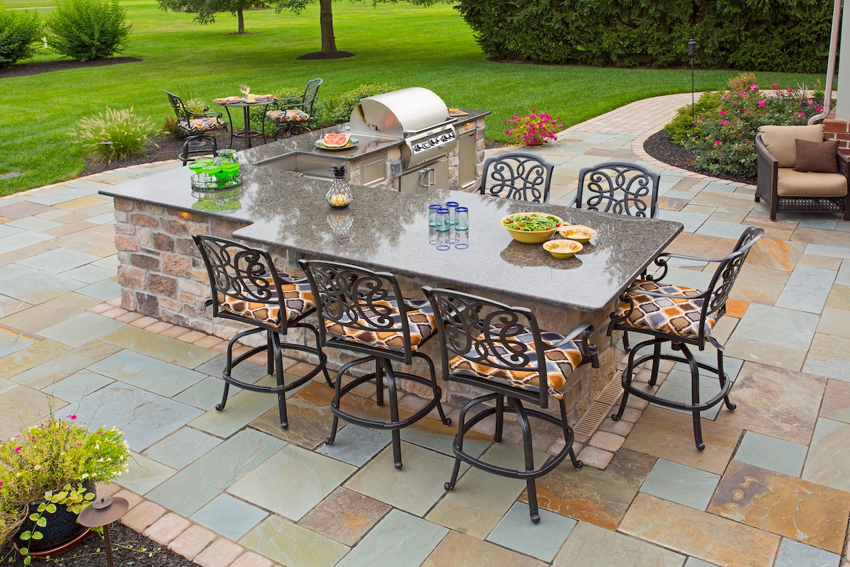 Outdoor kitchen and seating on flagstone patio designed by Earth Turf & Wood