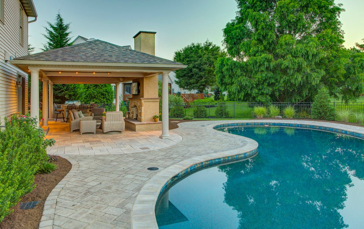 beautiful pool, pavilion, and outdoor fireplace designed by landscaping company